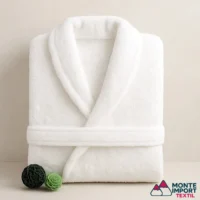 Albornoz blanco de rizo 100% algodón doblado sobre superficie clara con decoración lateral, imagen de Monte Import Textil