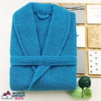 Albornoz turquesa de rizo 100% algodón doblado sobre fondo neutro, ideal para hostelería y spa – Monte Import Textil
